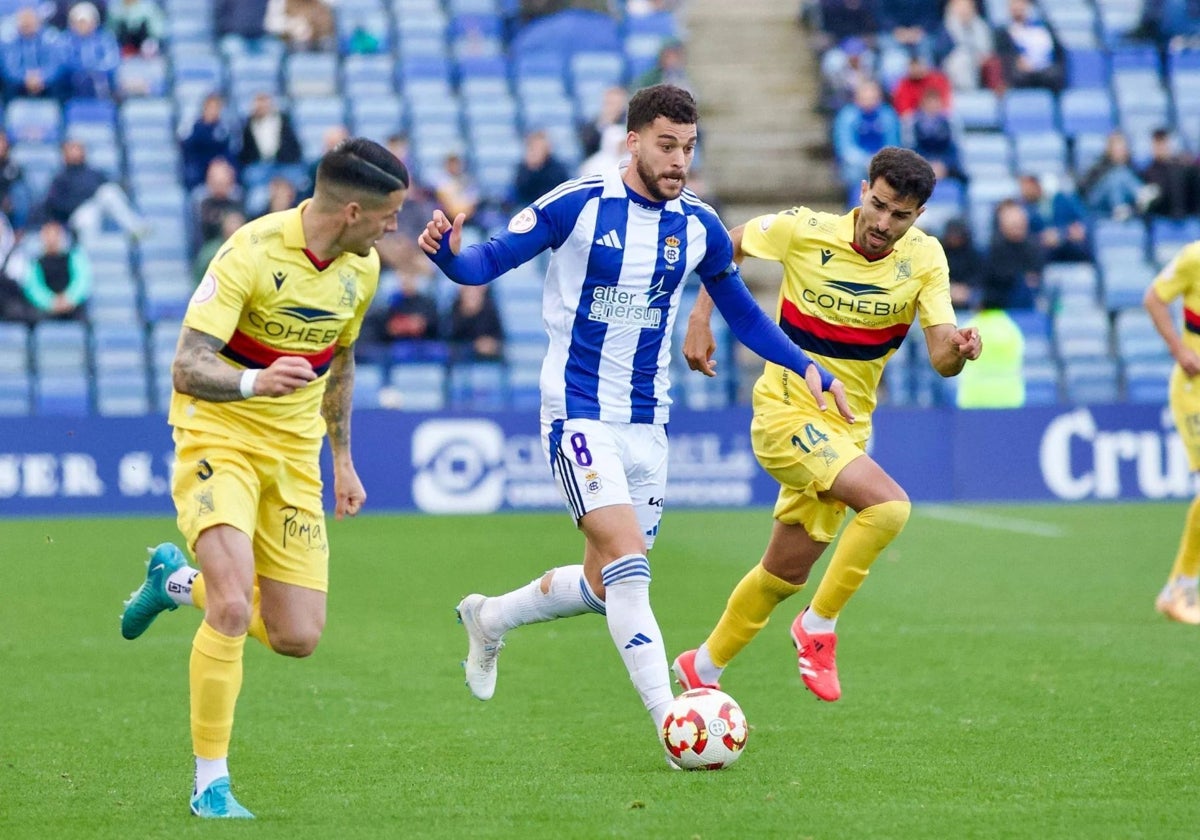 Luis Alcalde avanzando con el balón ante dos adversarios del Atlético Sanluqueño